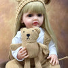 A lifelike 50 cm full silicone baby doll with blonde hair wearing a knitted bear hat and sweater.