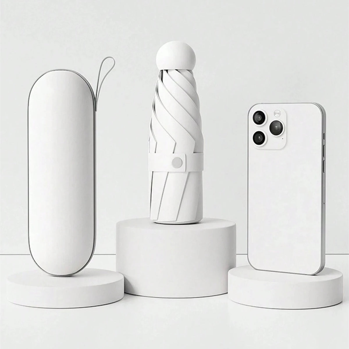 A white compact folding umbrella is displayed next to a white smartphone on a white surface.