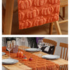 Orange textured table runner with pumpkin designs for a Halloween or Thanksgiving setting.