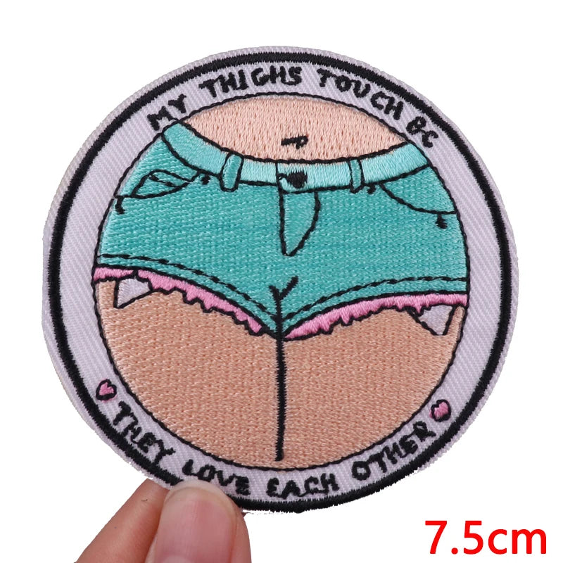 A circular embroidered patch featuring a stylized depiction of thighs with text and a heart design.