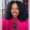 A close-up photo of a woman modeling a black kinky curly lace front wig with pink clothing.