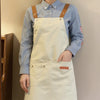 A person wearing a light blue shirt and brown suspenders with a cream-colored adjustable polyester kitchen apron.