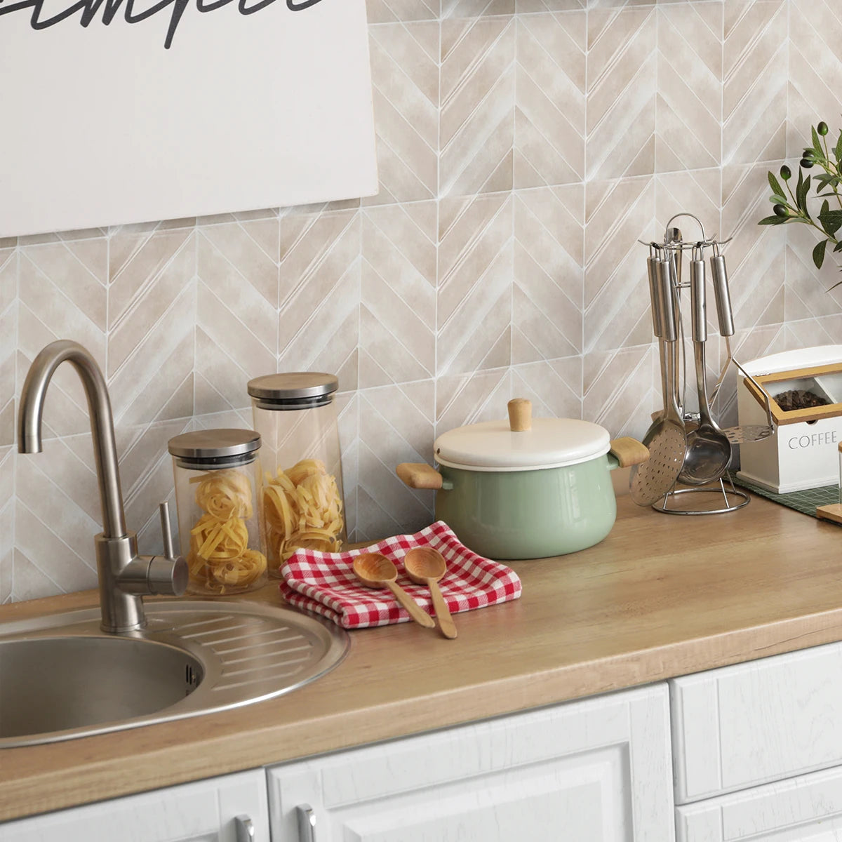 A kitchen counter display featuring glass jars of food, a green pot, and stainless steel utensils against a tiled backsplash.