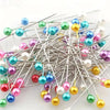 A collection of pearlized ball head sewing pins in various colors like blue, green, pink, and gold.