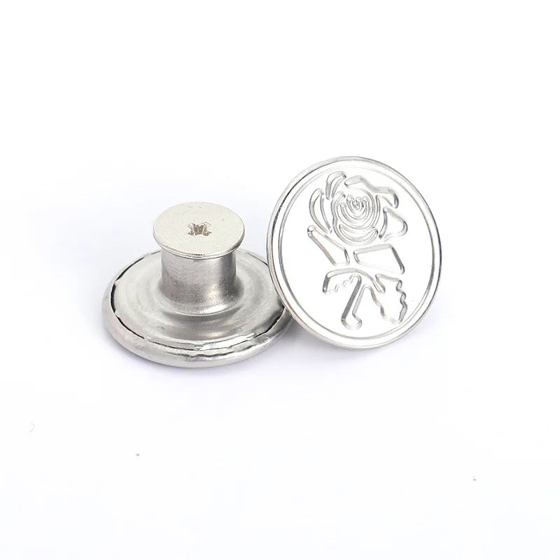 A silver metal button with a rose design is shown next to its flat, round base.