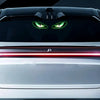 A silver car features a menacing green eye design on the grille and a red light strip across the front bumper.