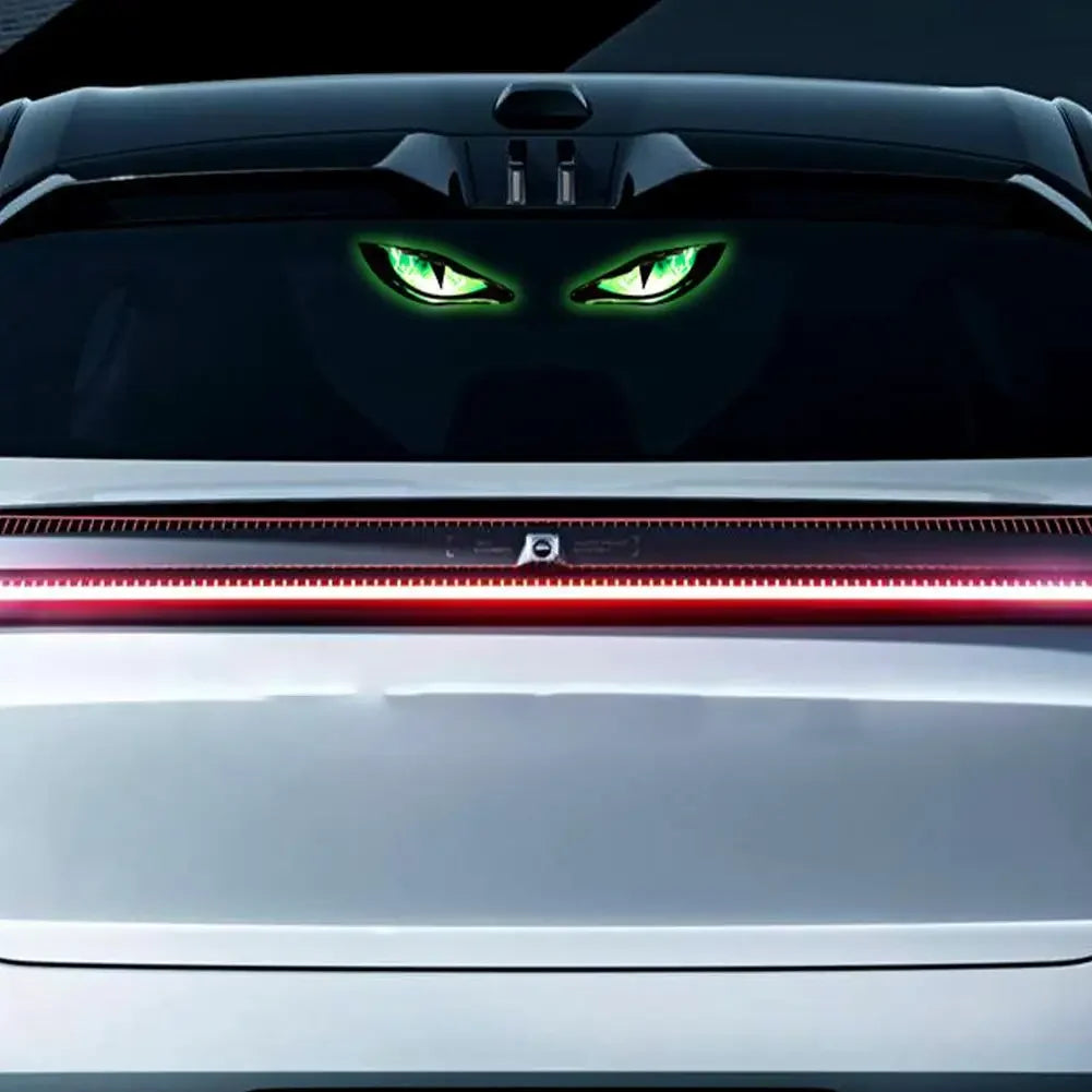 A silver car features a menacing green eye design on the grille and a red light strip across the front bumper.