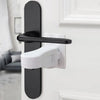 A close-up of a black and white door lever lock with an adhesive anti-open latch mechanism installed on a white door frame.