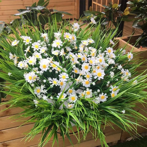 A dense arrangement of white and yellow artificial daisies with green foliage for indoor or outdoor decoration.