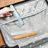 A hand is placing a light blue portable toothbrush into the clear, ventilated cover of a gray travel case.