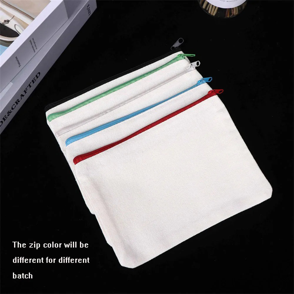 A stack of four white canvas tote bags with colored zippers are displayed on a black surface.