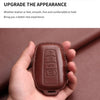 A hand holds a brown genuine leather car key case cover for Toyota models.
