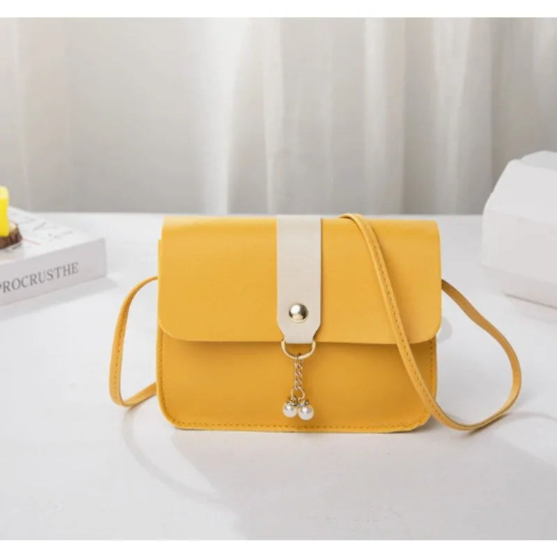 A yellow compact crossbody handbag with a white strap is displayed on a white surface.