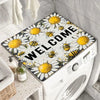 A white washing machine is covered with a floral print absorbent protective mat featuring yellow and black bees and daisies.