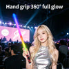 A blonde woman holds a glowing LED light stick in a concert setting.