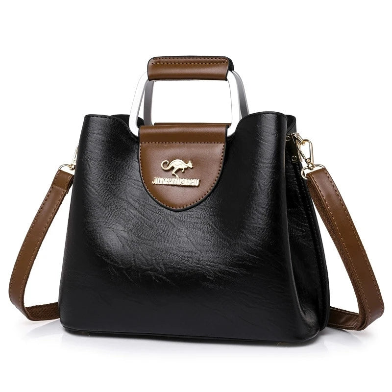 A black leather vintage crossbody tote bag with brown trim and a gold-toned logo.