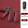 A red leather key case with a bracelet clasp and a black electronic remote featuring five buttons