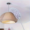 A modern pendant light featuring a woven gold shade and a fluffy gray microfiber duster head.