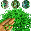 A hand holds a large bundle of green reusable vine strapping ties used for garden plant support.