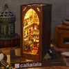 A wooden book nook kit with internal LED lighting displayed in a box, next to an ornate lantern and books.