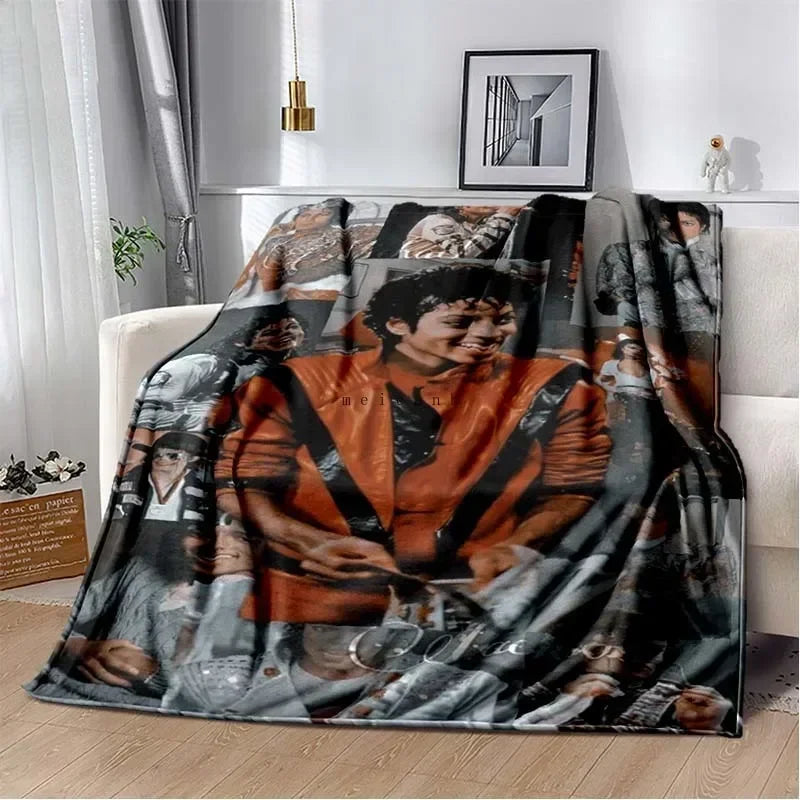 A dark flannel throw blanket featuring a collage of black and white photographs, including images of Michael Jackson.