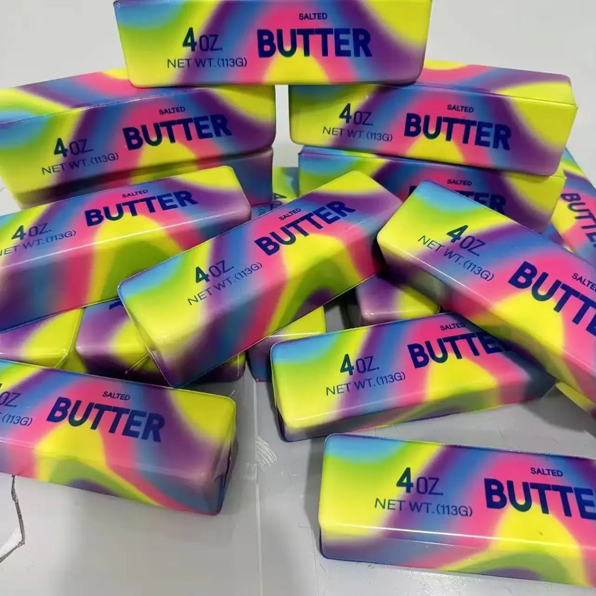 A collection of colorful butter-themed fidget sticks in various shades of yellow, pink, and purple.