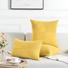 A set of two yellow corduroy patchwork throw pillow covers resting on a light gray sofa.