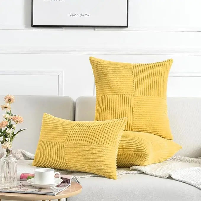 A set of two yellow corduroy patchwork throw pillow covers resting on a light gray sofa.