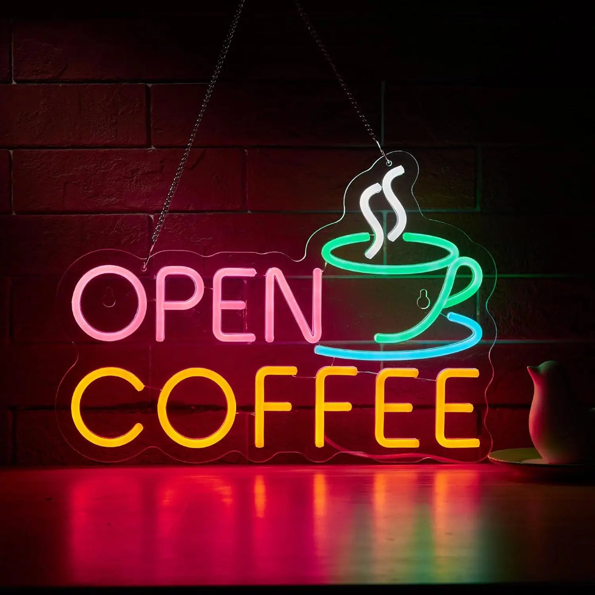 Neon sign shaped like a steaming cup of coffee with the words OPEN COFFEE glowing brightly on a brick wall.