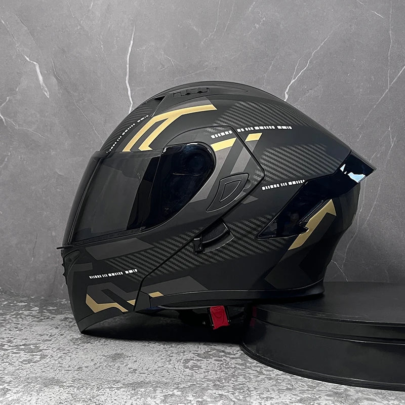 A black modular flip-up motorcycle helmet with gold accents is displayed on a dark surface.
