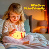 A young girl is smiling while holding a yellow axolotl night light on her face in a bedroom setting.