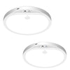 A white, round ceiling light fixture with a sensor and remote control visible against a white background.