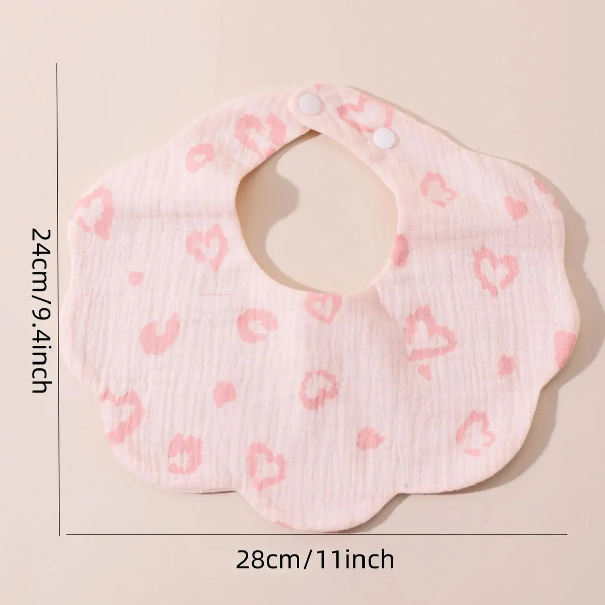 A pink, textured baby bib in a bandana style with a cutout and small pink hearts.