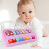 A baby is holding a pink xylophone piano with colorful wooden bars for musical play.