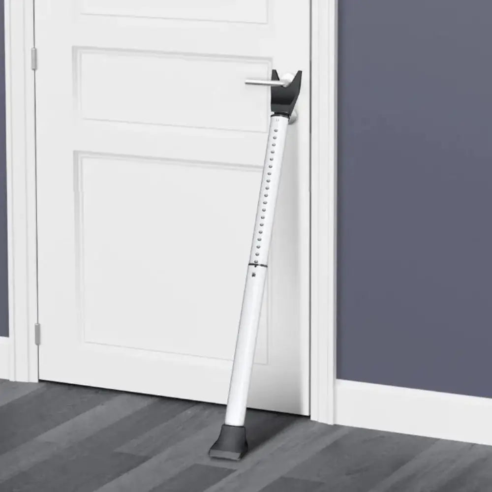 A white heavy-duty adjustable door security bar mounted on a door frame.