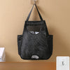 Black mesh garbage bag holder with hooks hanging on a beige wall