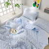 Light blue floral quilted blanket with matching pillows displayed on a white shelf.