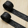 Black embossed foam wall panels in roll form lying on a light wooden surface.