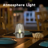 A glass candle holder with a flame is placed on a wooden table, demonstrating atmosphere light.