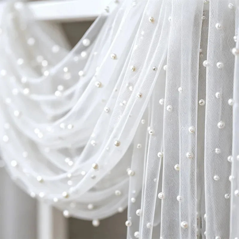 White sheer tulle fabric with delicate pearl embellishments draped elegantly