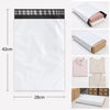 A white self-sealing mailing bag with a black header, shown next to folded garments.