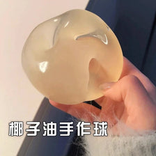 A close-up shot of a translucent, pale yellow squishy stress relief toy being held by a hand.