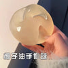 A close-up shot of a translucent, pale yellow squishy stress relief toy being held by a hand.