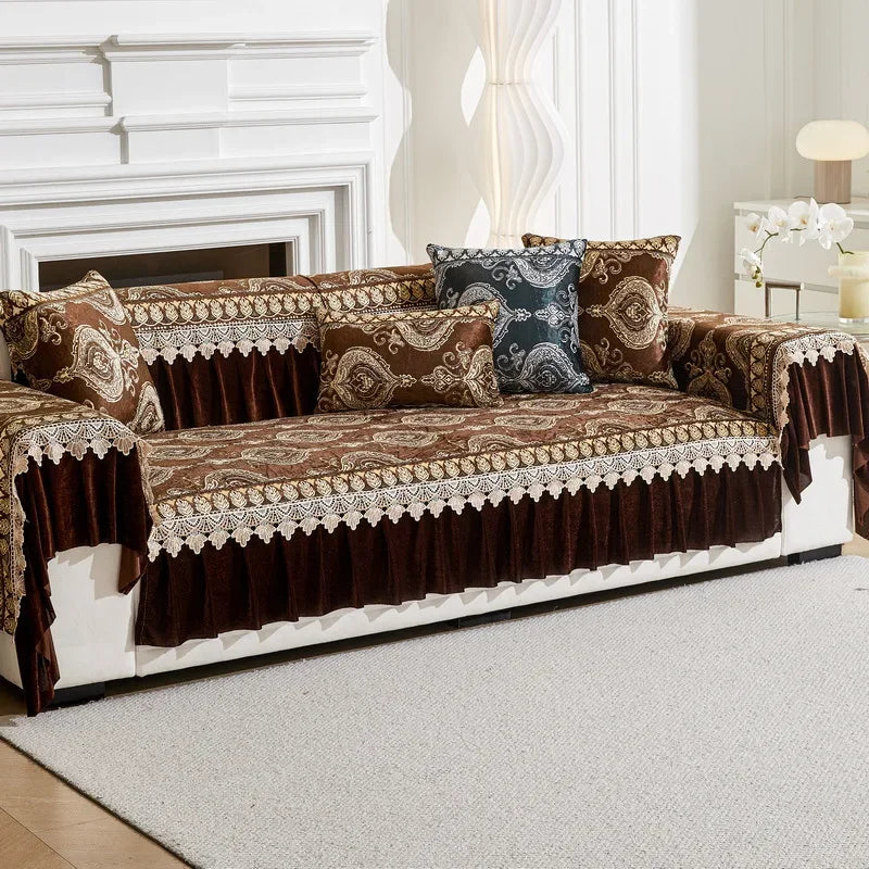 A brown and gold patterned sofa cover with decorative trim and accent pillows displayed on a white sofa.