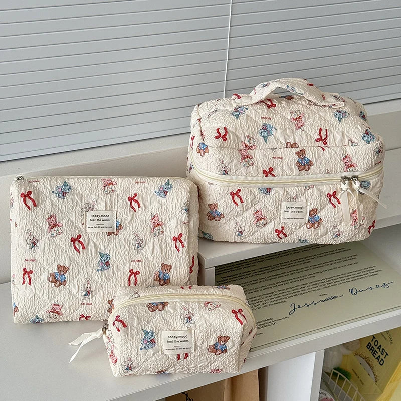 Lichtrosa Bären-Make-up-Tasche mit mehrreihigen Fächern auf weißem Untergrund.