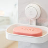 A white suction cup soap holder with a pink removable tray mounted on a wall.