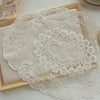 Elegant oval lace embroidered placemat with delicate floral patterns on a light beige fabric
