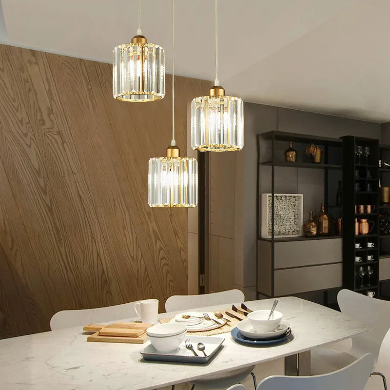 Three crystal pendant lights with iron frames hang above a white marble table in a modern interior.