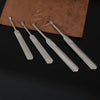 A set of four metal tools, including a groover and beveler, resting on a brown leather pad.
