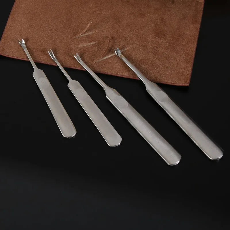 A set of four metal tools, including a groover and beveler, resting on a brown leather pad.